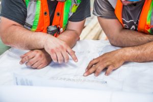 Two construction workers reviewing a blueprint together